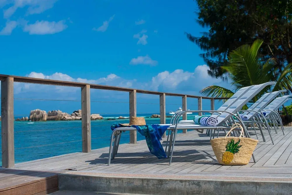 Transats alignés sur une terrasse en bois avec vue sur la mer et le ciel bleu.