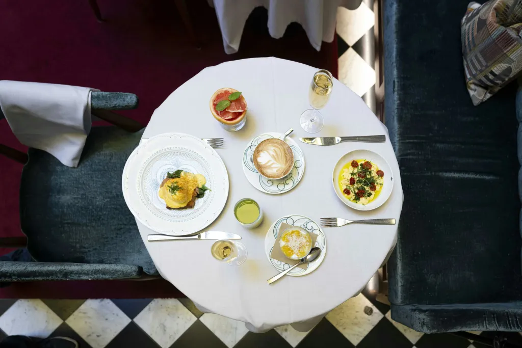 Une table ronde blanche est dressée avec des assiettes de nourriture et des boissons.