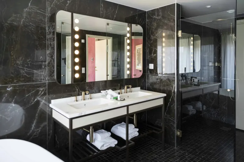 Une salle de bain moderne avec deux vasques et de grands miroirs éclairés.