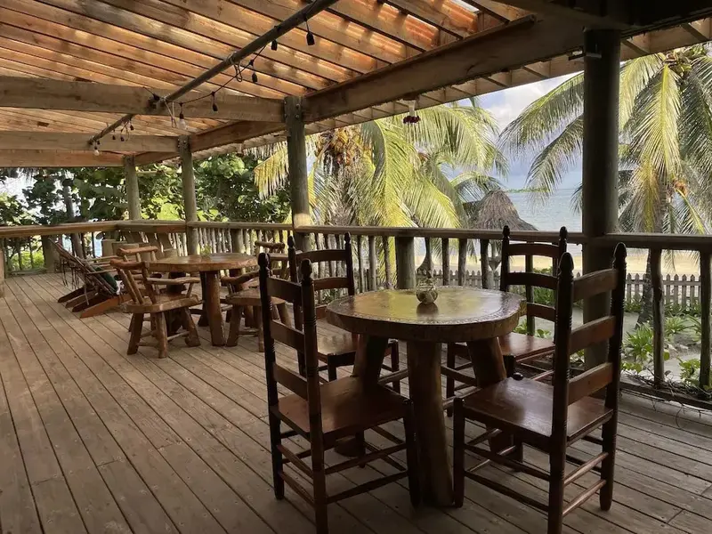 Terrasse en bois avec tables et chaises face à la mer.