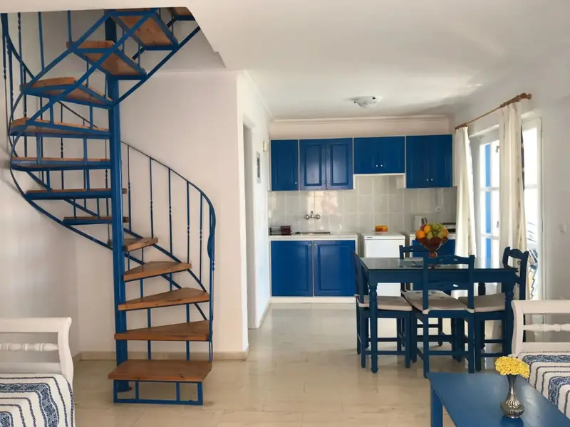 Une cuisine ouverte sur un espace repas avec un escalier en colimaçon bleu.