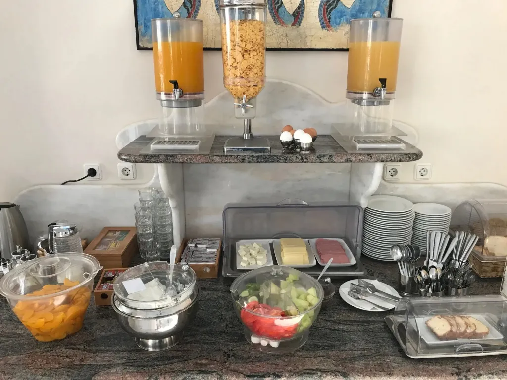 Un buffet propose des céréales, des jus de fruits, des fruits frais et des viennoiseries.