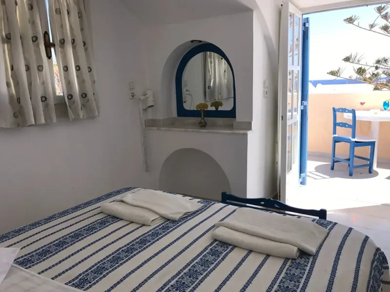 Une chambre lumineuse avec un lit recouvert d'une courtepointe rayée et une vue sur une terrasse.
