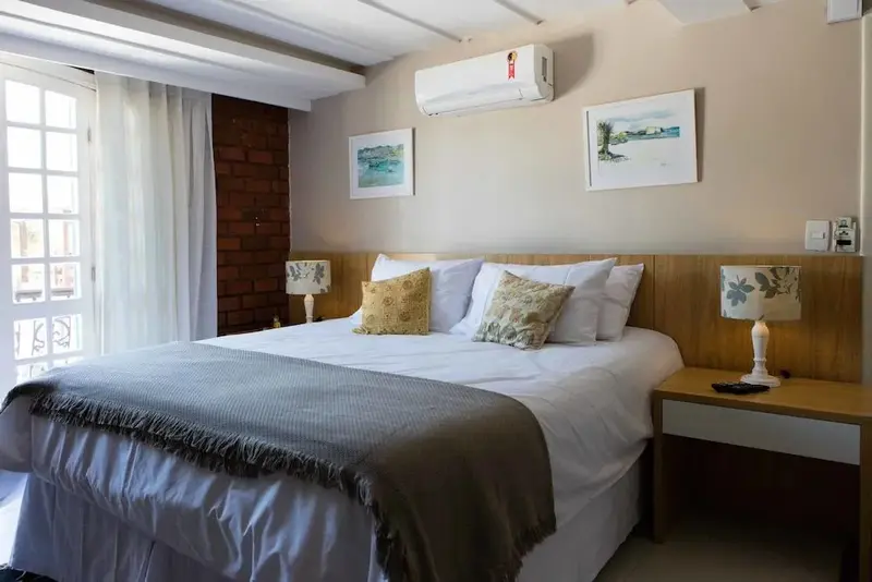 Une chambre lumineuse avec un grand lit et des tableaux décoratifs.