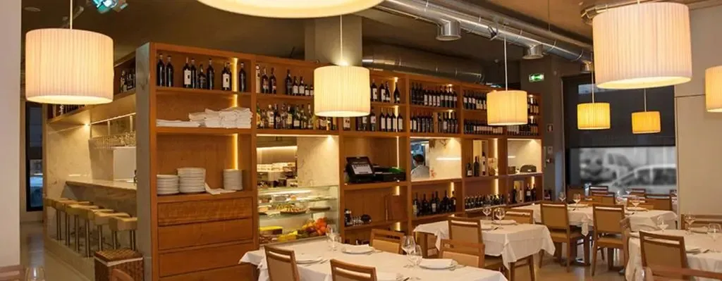 Une salle lumineuse avec un comptoir de boissons et des tables dressées pour le repas.
