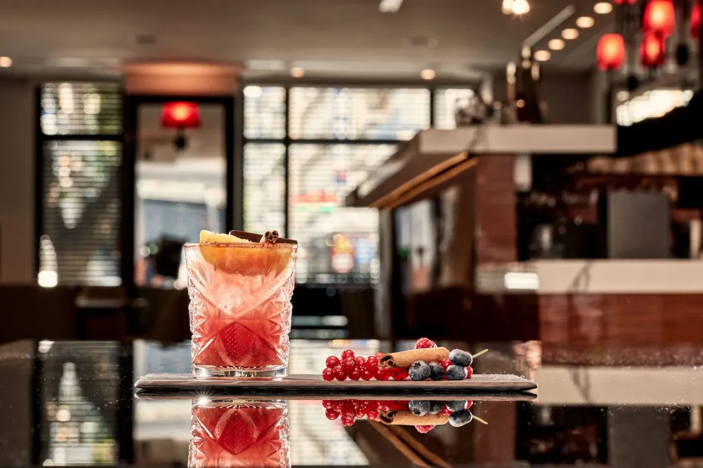 Un verre coloré est présenté sur un comptoir sombre, décoré de fruits frais.