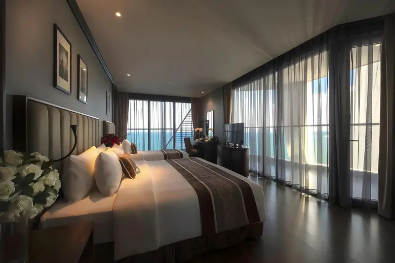 Une chambre spacieuse avec deux lits et une grande baie vitrée.