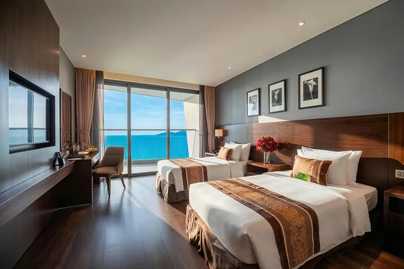 Chambre lumineuse avec deux lits et vue sur la mer.