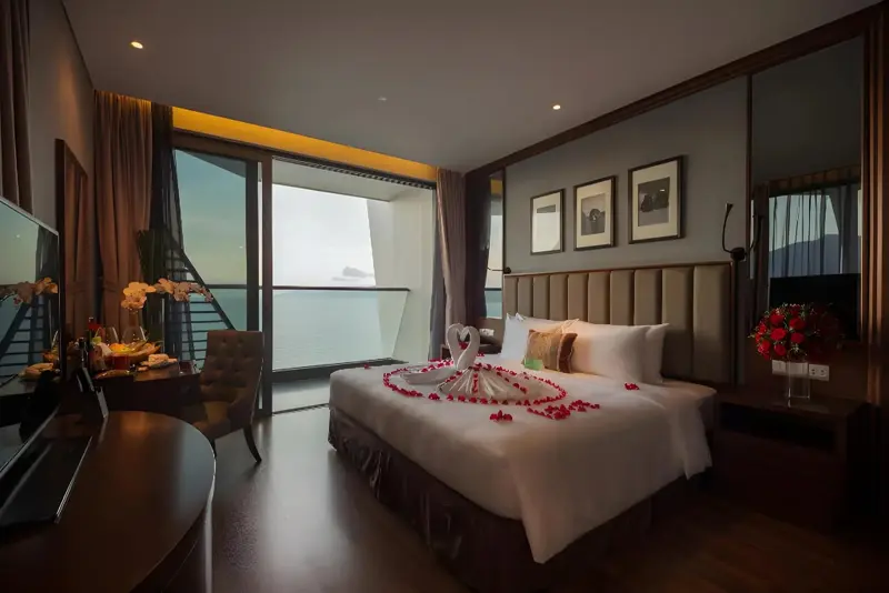 Une chambre spacieuse avec un grand lit décoré de pétales de fleurs et une vue sur la mer.
