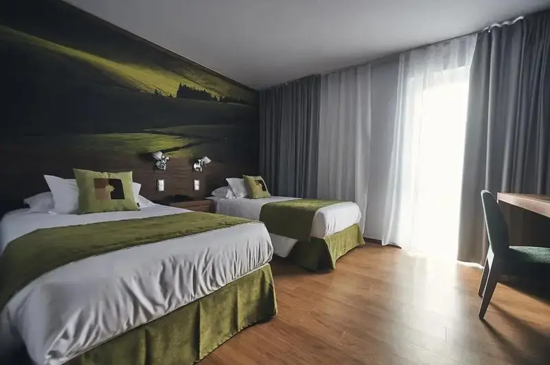 Une chambre avec deux lits simples et un bureau près d'une fenêtre.