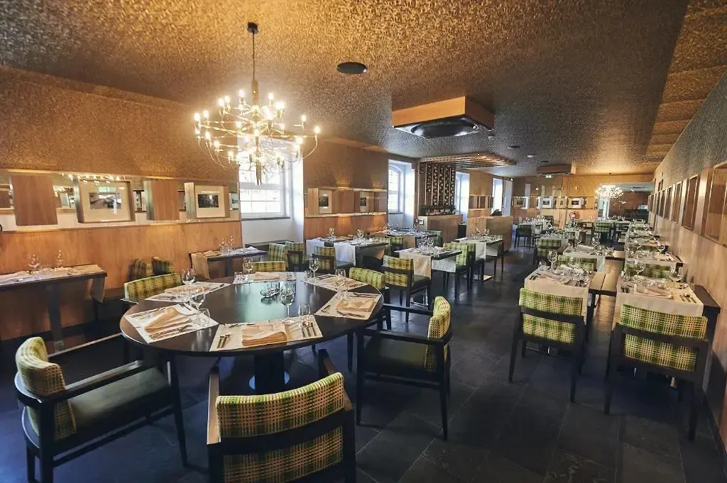 Une salle de restaurant lumineuse avec des tables dressées et des lustres.