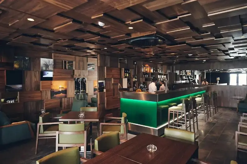 Un bar moderne avec un comptoir illuminé et des tables.
