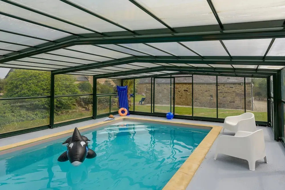 Piscine intérieure avec un jouet flottant et des chaises longues.