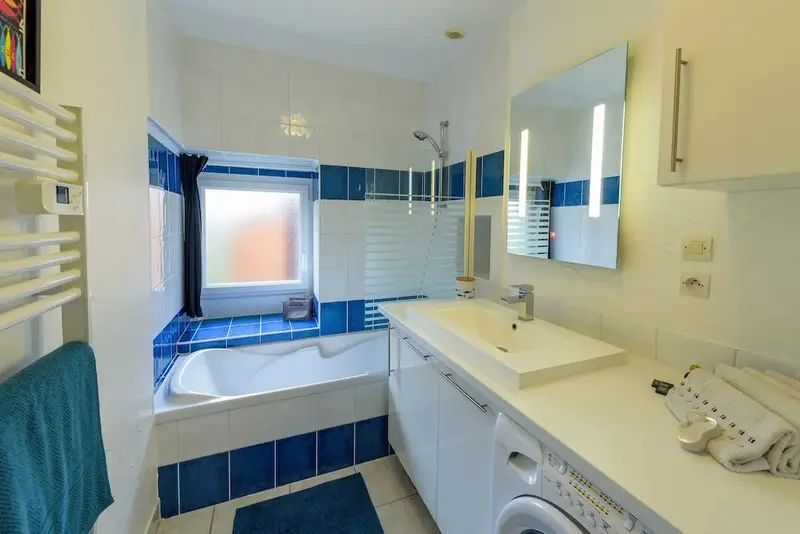 Une salle de bain lumineuse avec baignoire et lavabo.