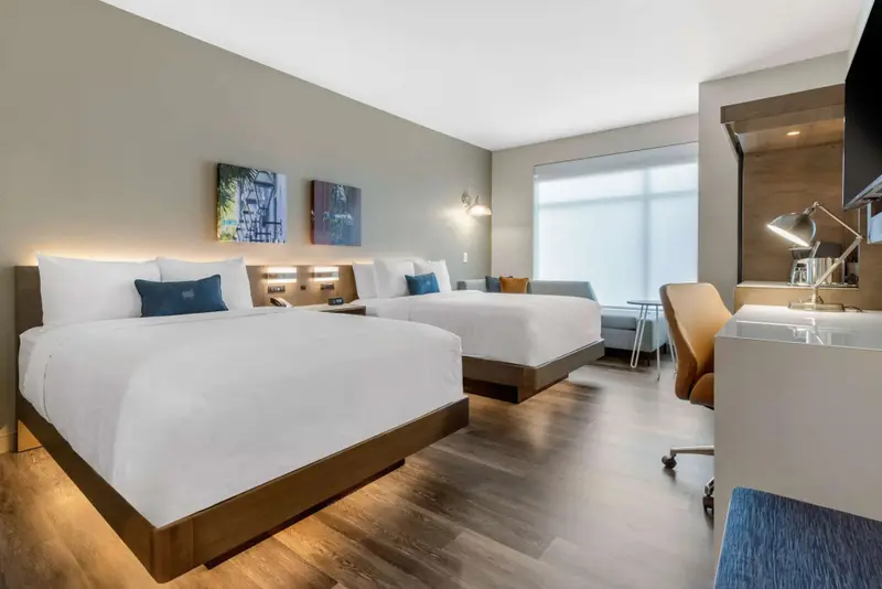 Une chambre lumineuse avec deux lits et un espace de travail.