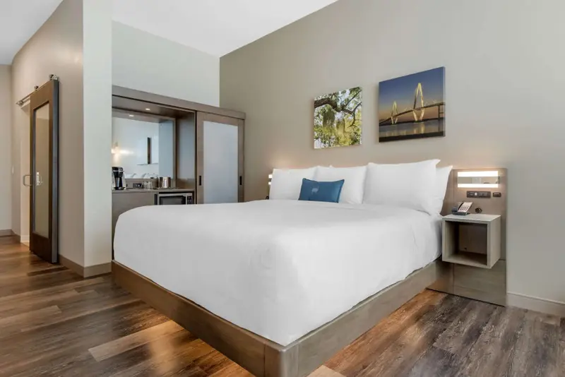 Une chambre lumineuse avec un grand lit recouvert d'une couette blanche.