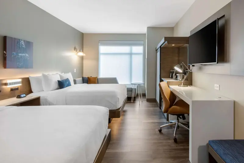 Une chambre lumineuse avec deux lits et un espace bureau.