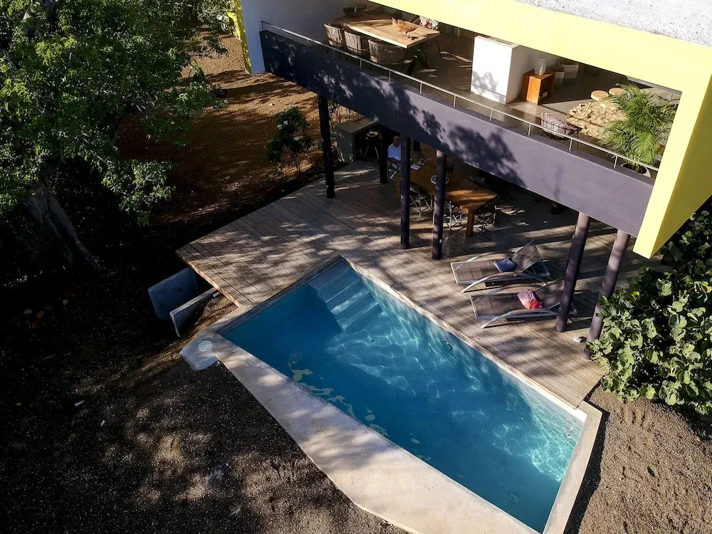 Une piscine rectangulaire avec des marches et des transats sur une terrasse en bois.