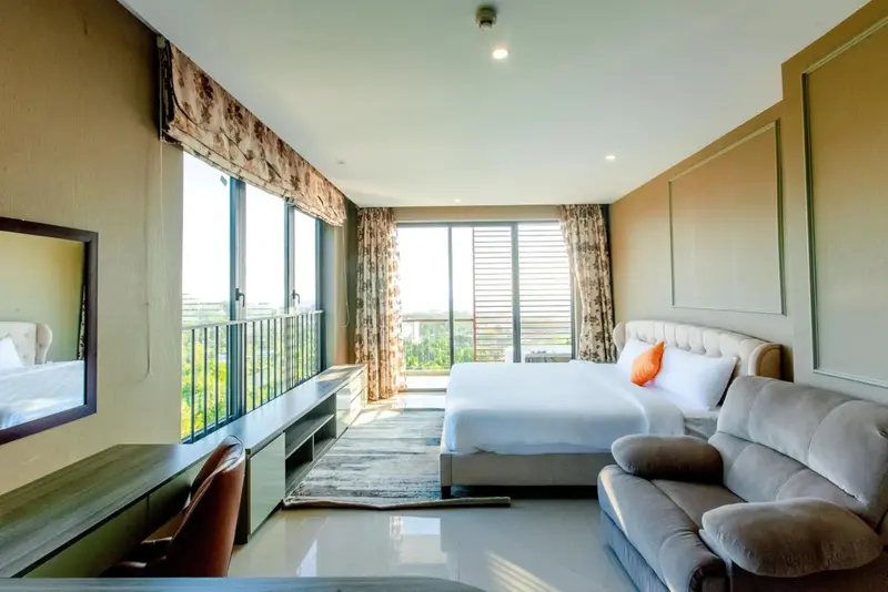 Une chambre lumineuse avec un canapé et un accès à un balcon.