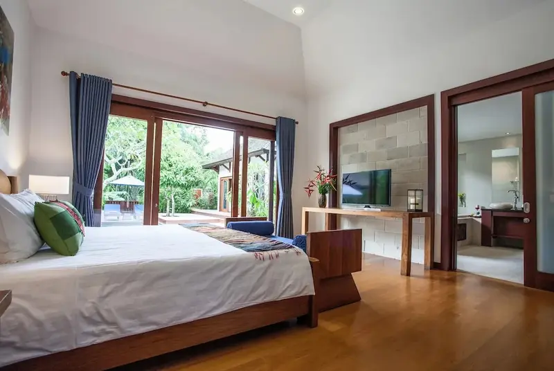 Une chambre lumineuse avec un grand lit et un accès à une piscine.