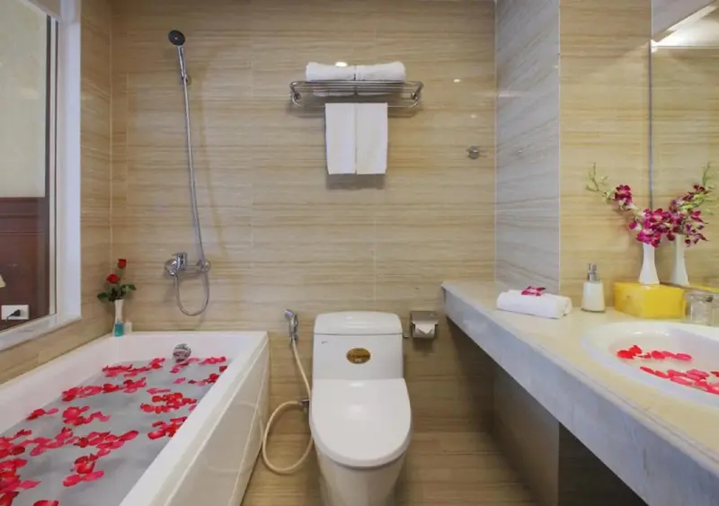 Une baignoire remplie d'eau et de pétales de fleurs dans une salle de bain lumineuse.