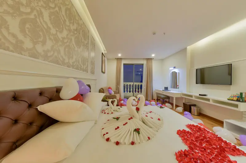 Une chambre d'hotel est decorée de ballons et de serviettes en forme de cygnes.
