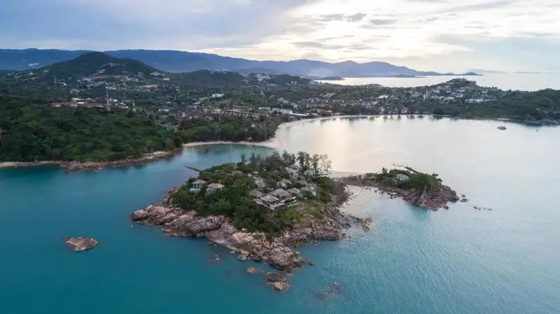 Vue aérienne d'une presqu'île rocheuse avec des bâtiments et une plage.