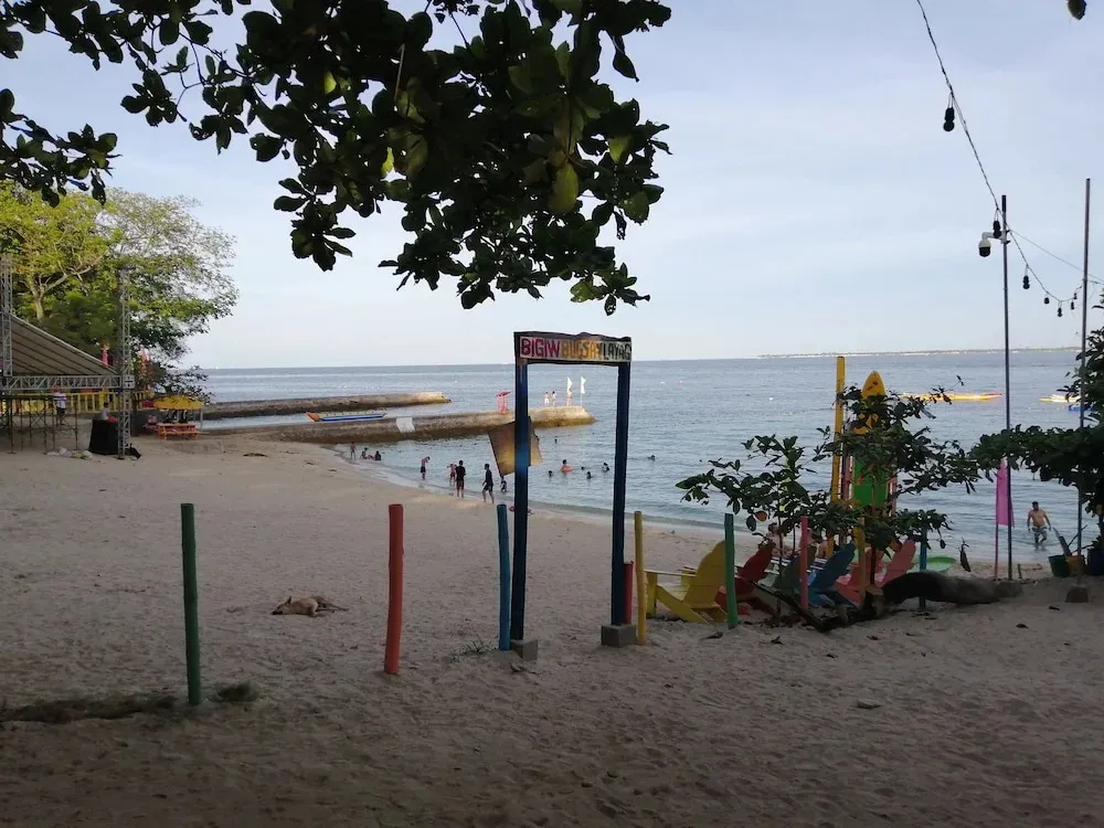 Une plage de sable avec des personnes se baignant et des chaises longues colorées.