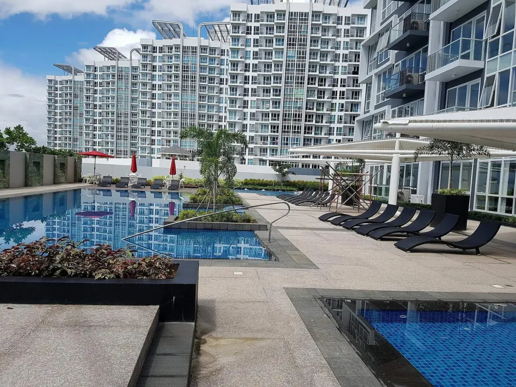 Piscine avec transats et bâtiments modernes en arrière-plan.