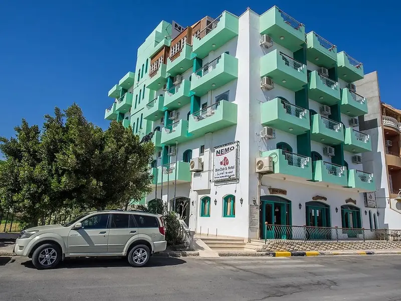 Bâtiment à plusieurs étages avec des balcons et une façade colorée, devant une rue.