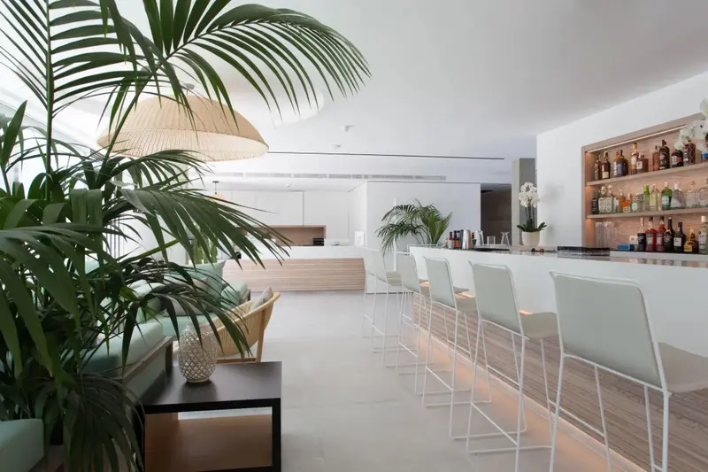 Un espace lumineux avec un bar et des canapés verts.