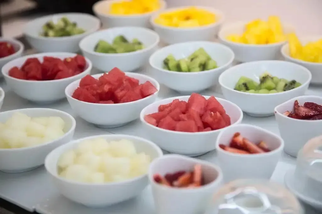 Assortiment de fruits frais coupés dans des petits bols blancs.