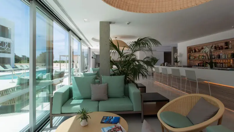 Espace de détente intérieur avec canapés verts et bar lumineux.