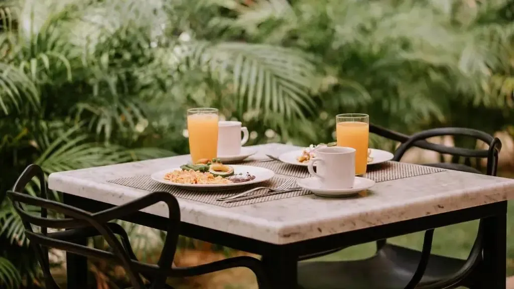Une table est dressée avec des plats et des boissons dans un cadre verdoyant.