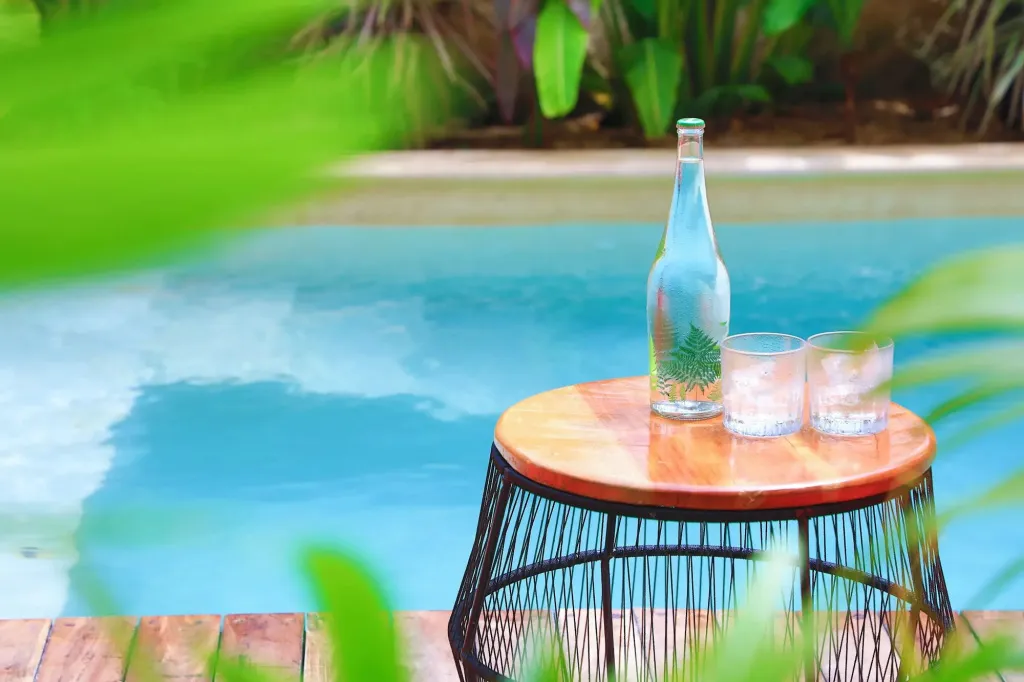 Une table basse en bois avec des boissons fraîches près d'une piscine.