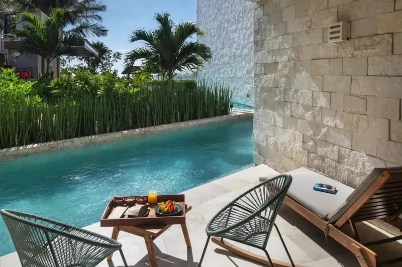 Une table servie de boissons et de fruits se trouve sur une terrasse avec des chaises et un transat.