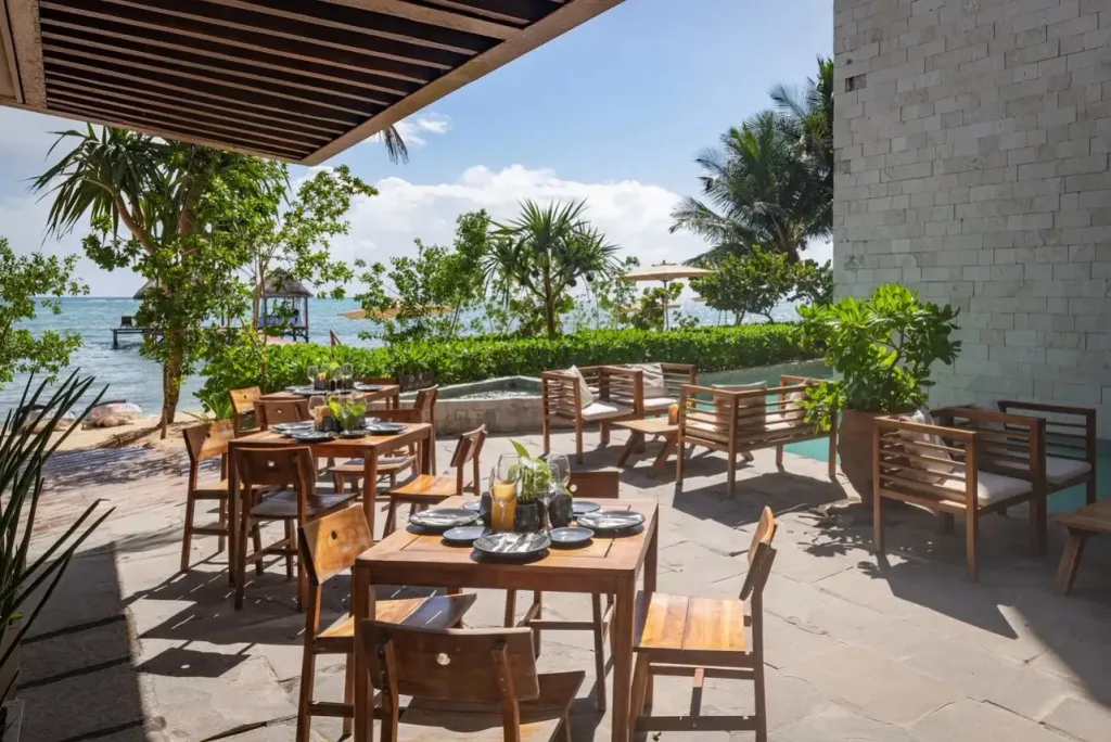 Tables dressées en terrasse ombragée près d'une végétation luxuriante.