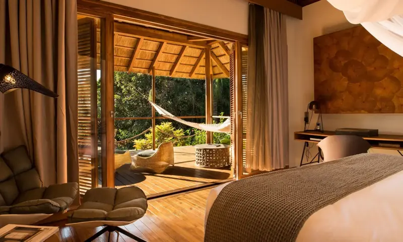 Une chambre lumineuse s'ouvre sur une terrasse avec un hamac.