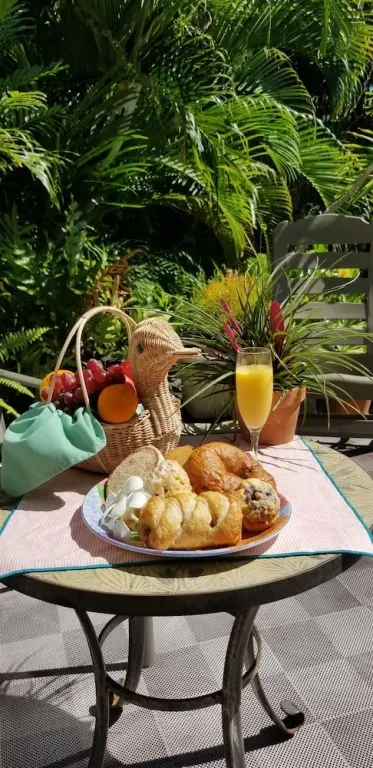 Une table ronde présente un petit-déjeuner avec des viennoiseries et un jus d'orange.