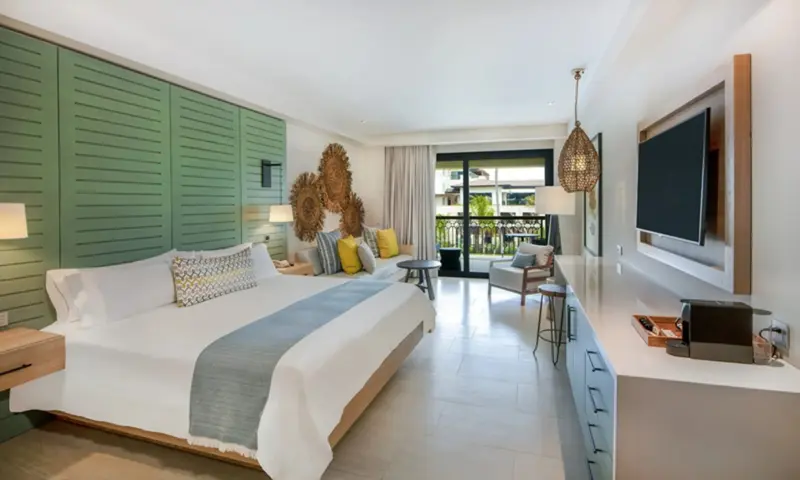 Une chambre lumineuse avec un grand lit et un accès à un balcon.