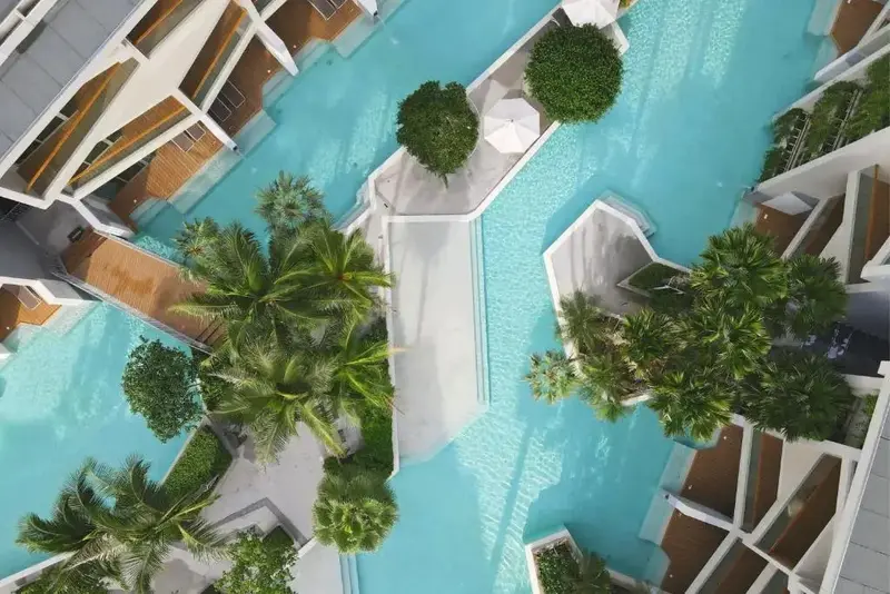 Vue aérienne d'un complexe hôtelier avec des piscines sinueuses et une végétation luxuriante.