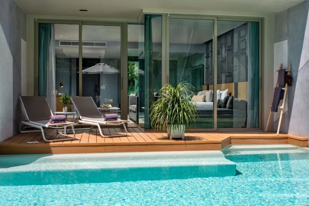 Terrasse avec transats et piscine privée devant une baie vitrée.