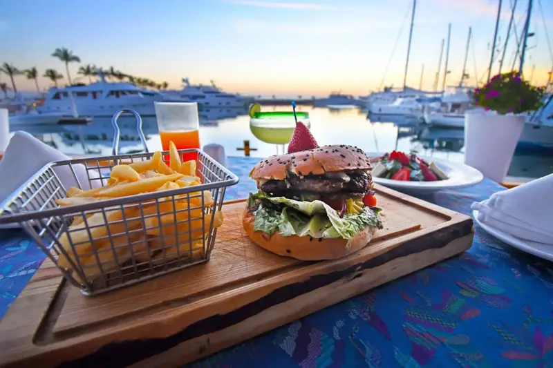 Un repas est servi sur une table en bord de marina au coucher du soleil.