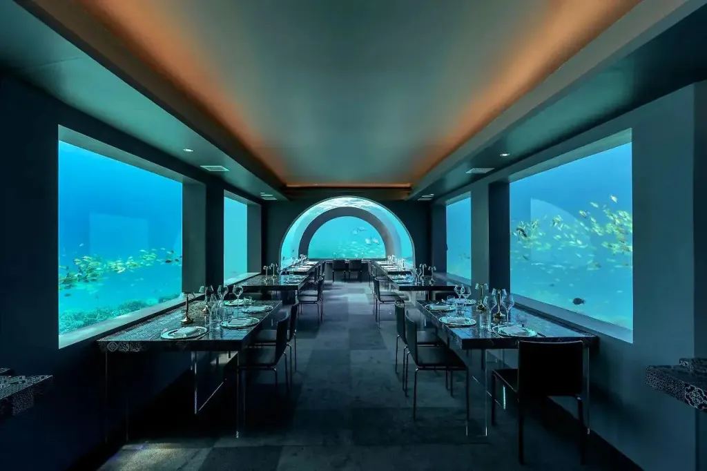 Une salle de restaurant élégante avec de grandes fenêtres donnant sur un paysage marin.