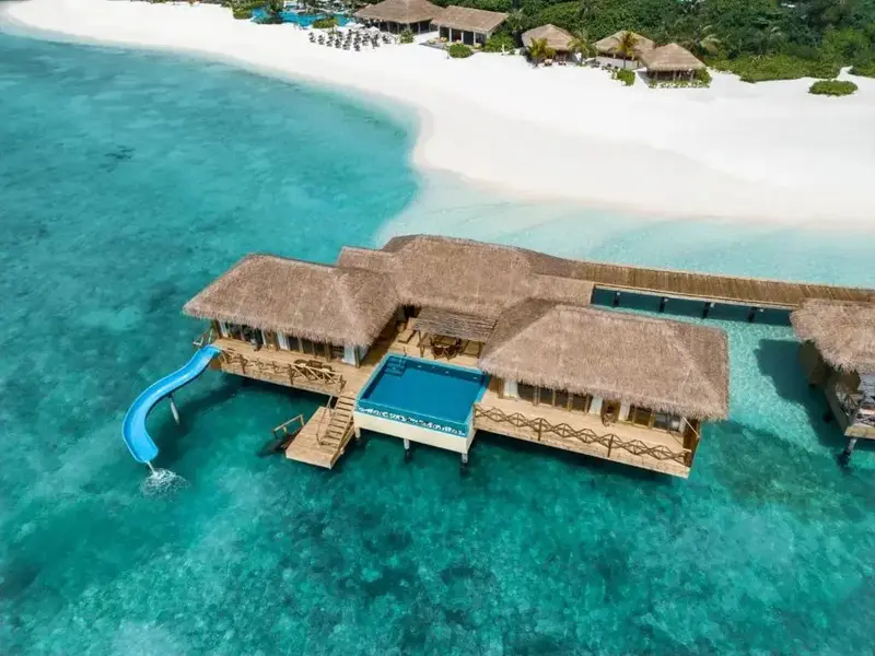 Vue aérienne d'une villa sur pilotis avec piscine et toboggan.