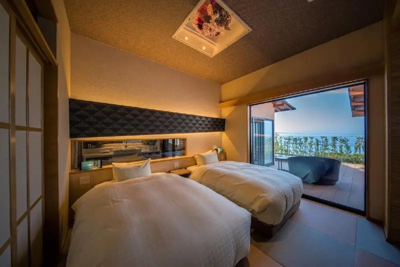 Une chambre lumineuse avec deux lits simples donnant sur une vue mer.