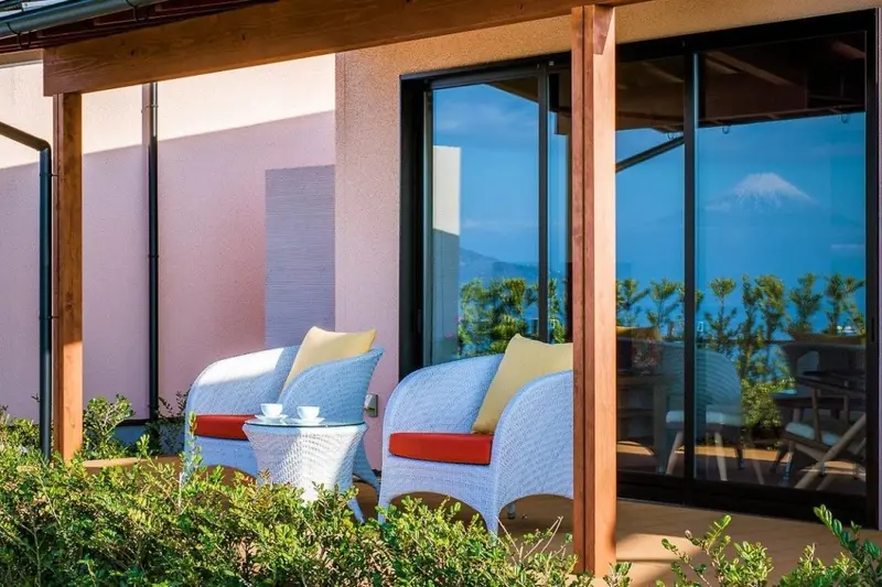 Terrasse avec mobilier en osier donnant sur un paysage montagneux.