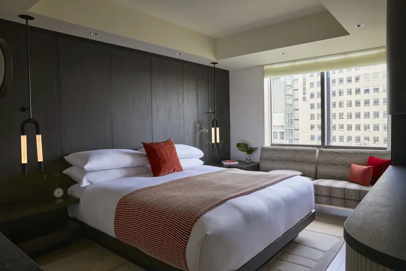 Une chambre moderne avec un grand lit et un coin salon près d'une fenêtre.