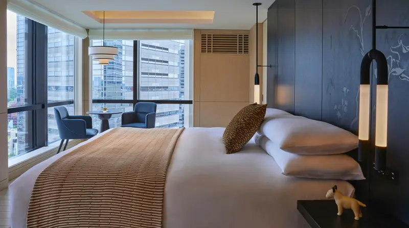Une chambre lumineuse avec un grand lit et un coin salon près de la fenêtre.