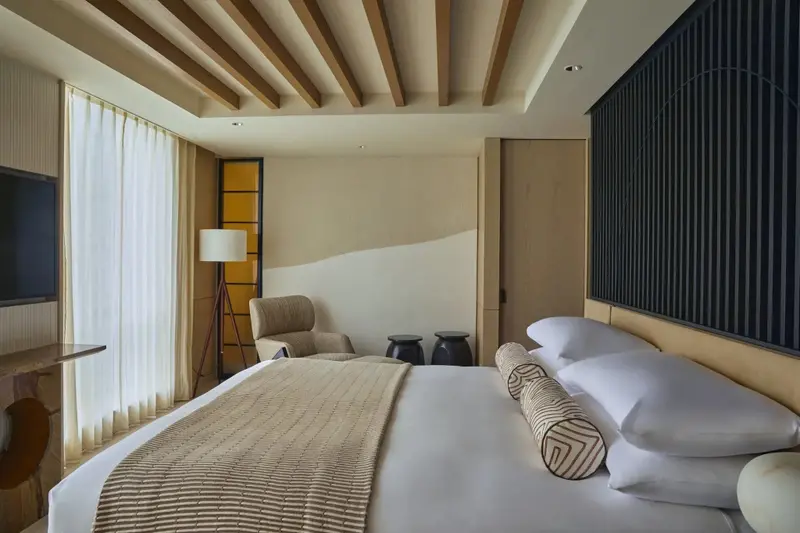 Une chambre lumineuse avec un grand lit et un fauteuil.
